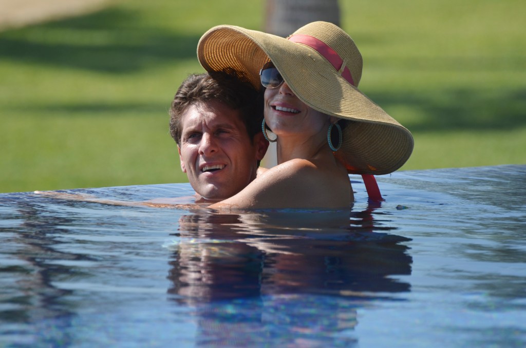 Bethenny Frankel and Jason Hoppy hugging in a pool; Bethenny is wearing a large sun hat