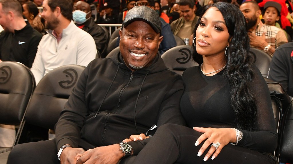 Porsha Williams and Simon Guobadia wearing black and sitting together at a basketball game