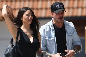Jax Taylor and Paige Woolen walking together; she's wearing all black and has her arm in the air; he's wearing a denim jacket and a black hat