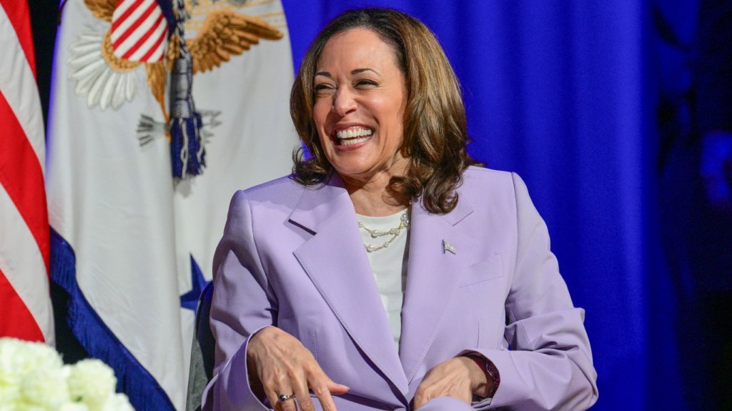 Kamala Harris wearing a lavender suit and laughing