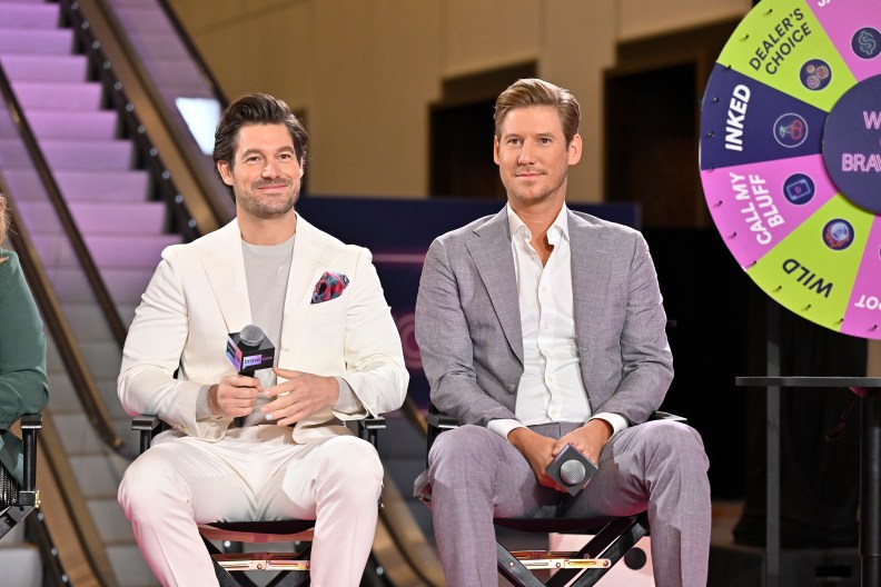 Austen Kroll and Craig Conover wearing suits and sitting on stage at BravoCon 2023
