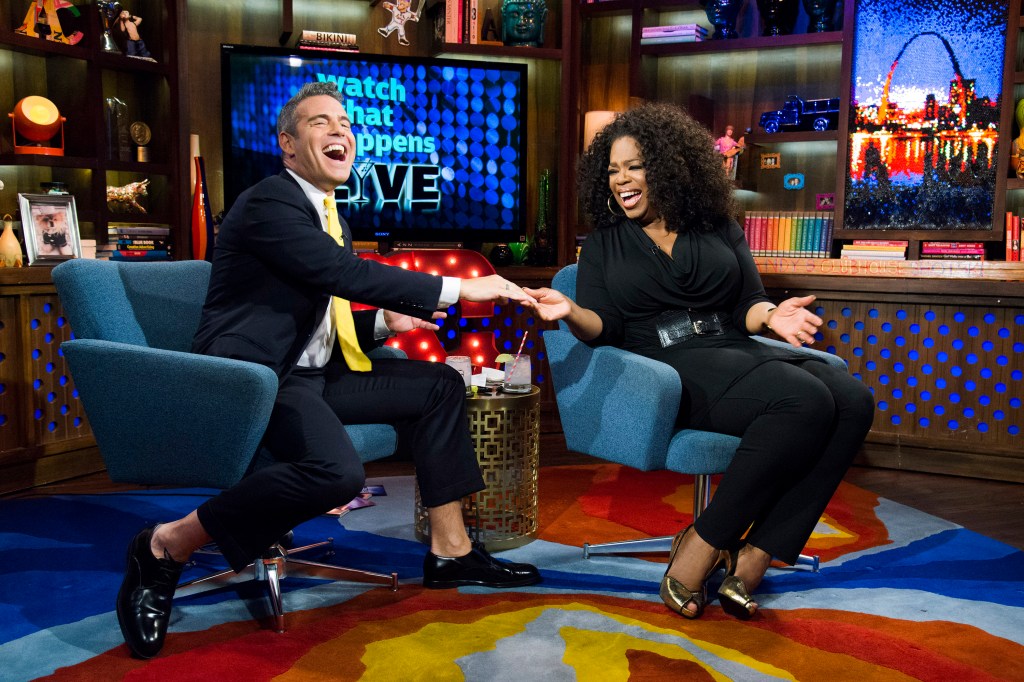 Andy Cohen and Oprah Winfrey high-fiving and laughing during a 2013 Watch What Happens Live interview