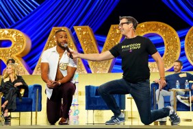 Amir Lancaster on one knee on stage at BravoCon along with Jerry O'Connell who is holding a microphone