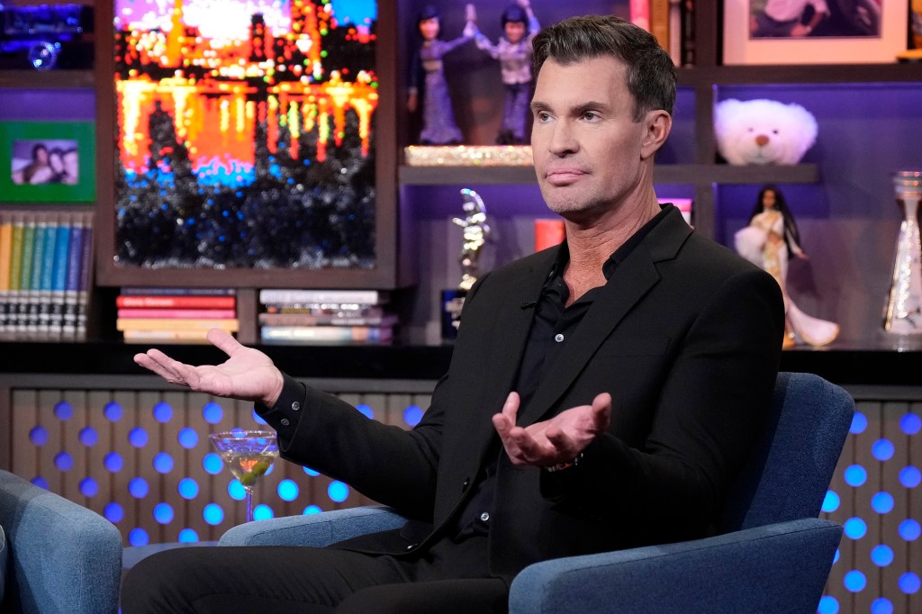 Jeff Lewis in a black suit on Watch What Happens Live holding his hands up in disbelief