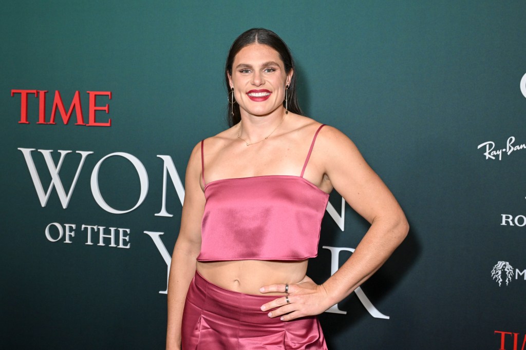 Ilona Maher posing in a pink two-piece outfit with her hands on her hips