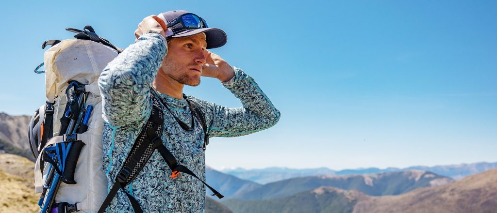 Corry Jones holding his head and looking over a cliff on Race to Survive: New Zealand