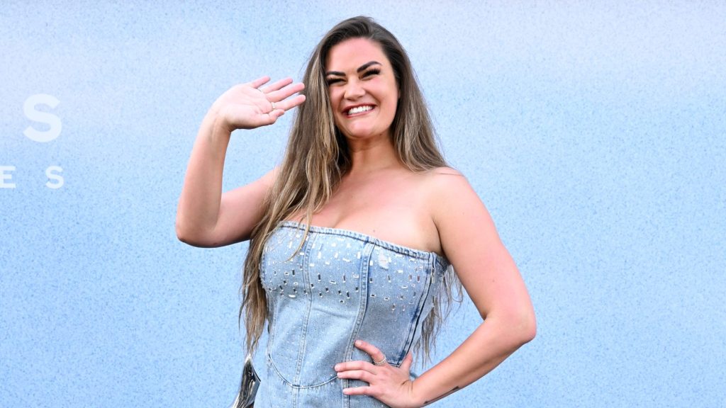 Brittany Cartwright smiling and waving in an interesting denim outfit.