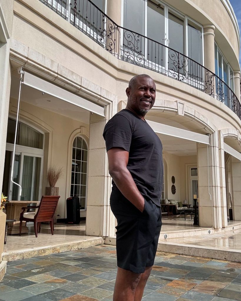 Simon Guobadia posing in front of a mansion 