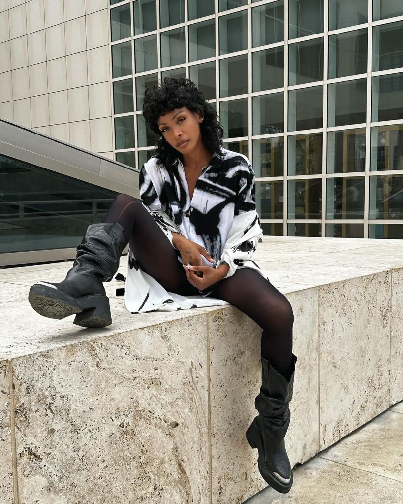 Dawn Richard posing on a city street with her boots kicked up