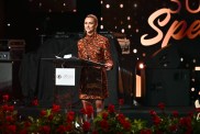 Lala Kent smiling and standing at a podium