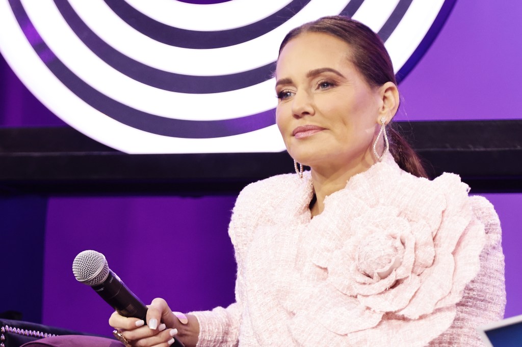 Meredith Marks holding a microphone and wearing a pink blazer at BravoCon 2023