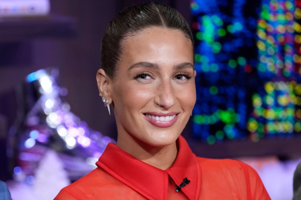 Amanda Batula in a red shirt smiling into the camera.