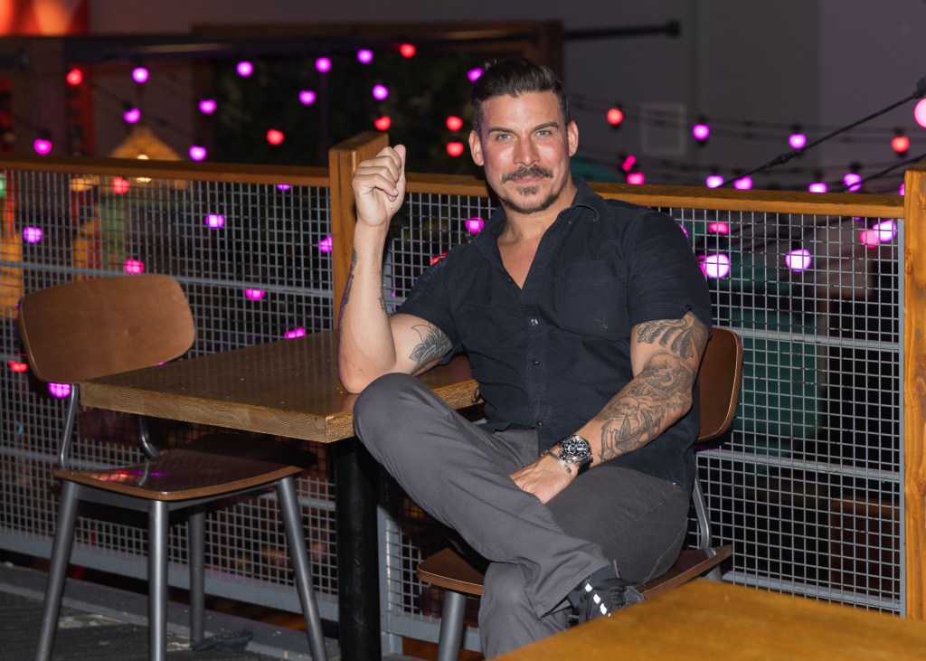 Jax Taylor sitting at a table with his legs crossed