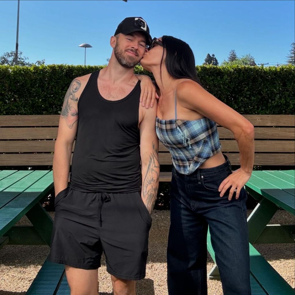 Nikki Garcia and Artem Chigvintsev posing together; she's kissing ihm on the cheek 