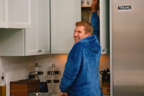 Todd Chrisley in a blue robe looking back at he reaches into a cabinet