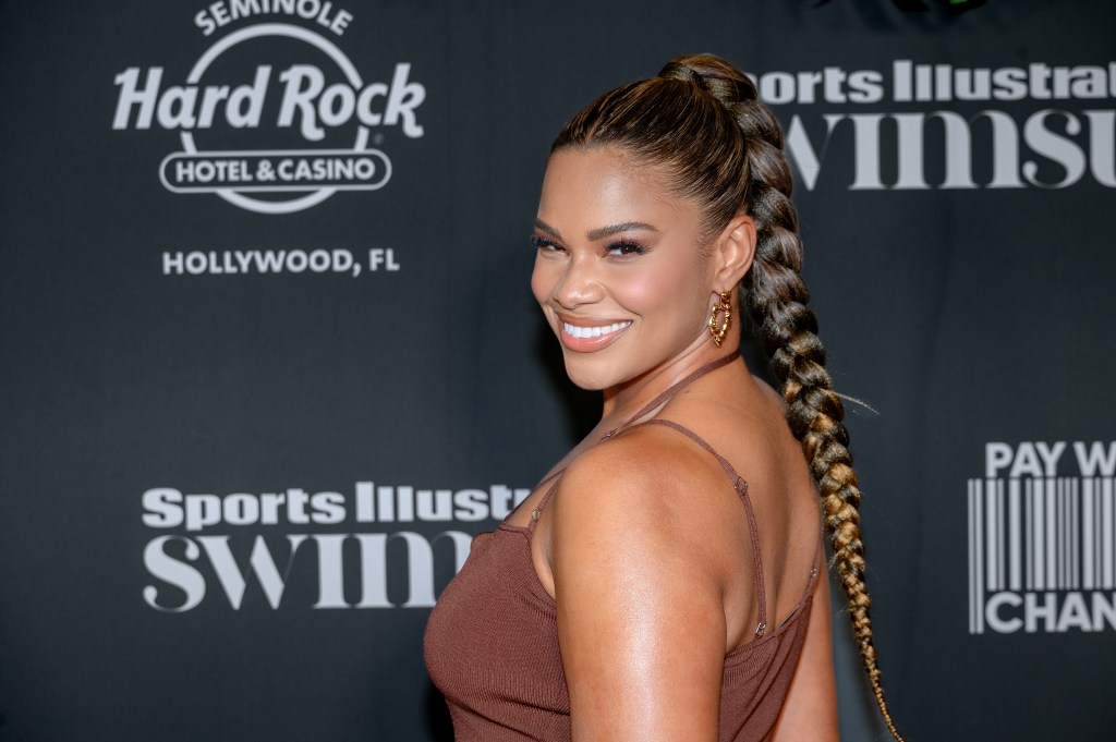 Kamie Crawford in a brown dress doing an over the shoulder pose